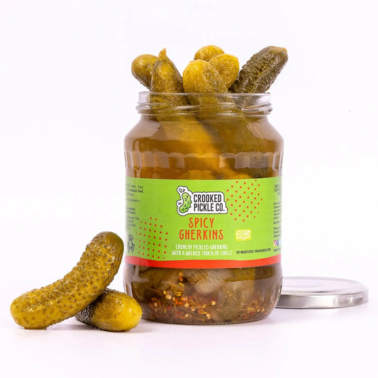 Jar of Crooked Pickle Co. spicy gherkins pickles with bright green cucumbers and spicy seasoning visible in the jar.