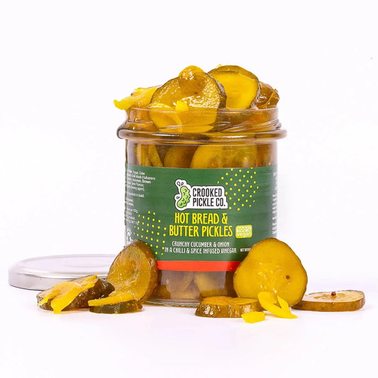 Jar of Crooked Pickle Co. hot bread and butter pickles with sliced cucumbers and spices in clear glass jar.