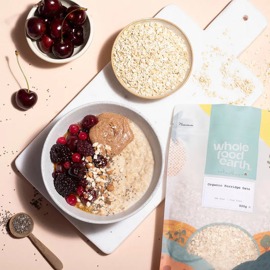 A bowl of organic porridge oats from Whole Food Earth with a spoon, surrounded by fresh ingredients for a wholesome breakfast.