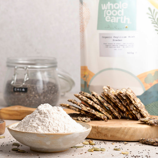Organic Psyllium Husk Powder by Whole Food Earth in a jar, shown in a natural setting with scoops and fresh ingredients.