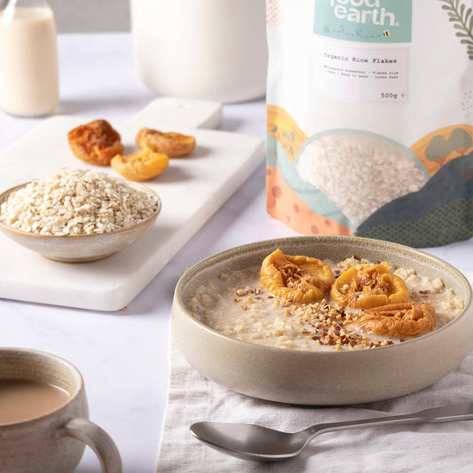 Organic rice flakes from Whole Food Earth displayed in a bowl with a spoon on a wooden table, emphasizing natural, healthy grains.