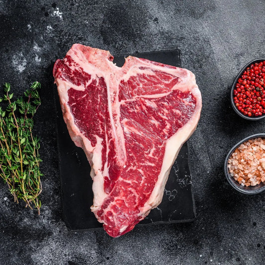 Dry-aged beef T-bone steak from Primrose Herd, showcasing a well-marbled cut with a rich, juicy appearance.
