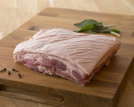 Fresh pork belly on the bone from Primrose Herd, showcasing crispy skin and tender meat in a close-up shot.