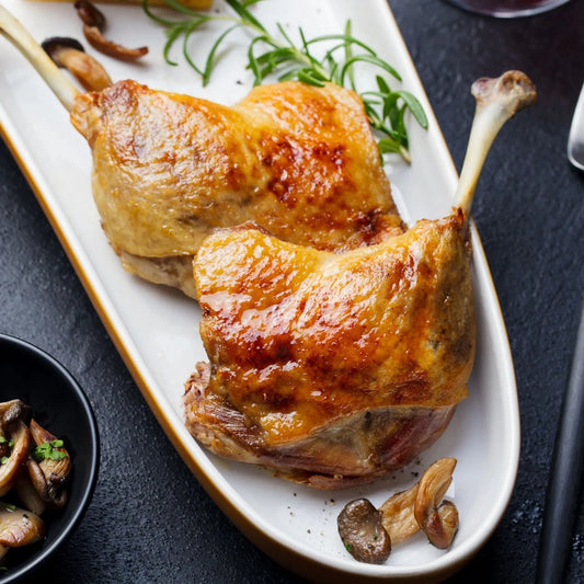 Primrose Herd Cornish free-range confit duck legs served on a plate, showcasing golden, tender duck meat with crispy skin.