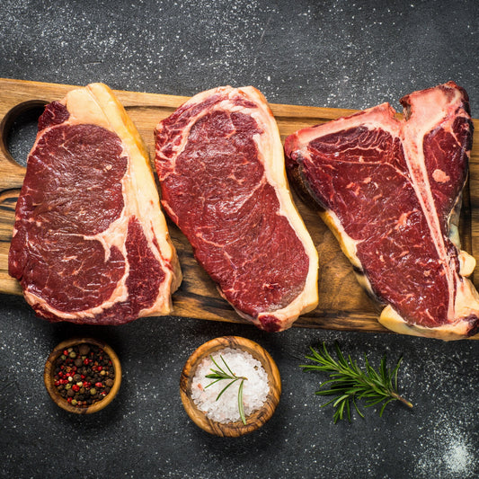 Three grass-fed beef steaks from Primrose Herd, fresh and juicy, displayed on a wooden cutting board.