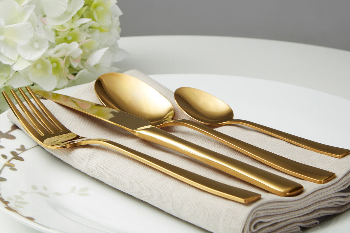 Orsina Glow 16-piece gold cutlery set with forks, knives, spoons, and teaspoons arranged on a table for elegant dining.