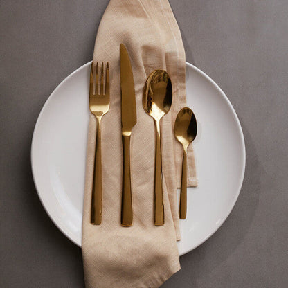 Orsina Glow 16-piece gold cutlery set with fork, knife, spoon, and teaspoon arranged on a white surface.