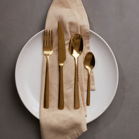 Orsina Glow 16-piece gold cutlery set with fork, knife, spoon, and teaspoon arranged on a white surface.
