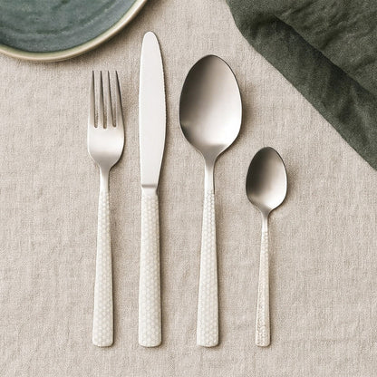Casablanca 16-piece stainless steel cutlery set by Orsina, including forks, knives, spoons, and teaspoons arranged on a table