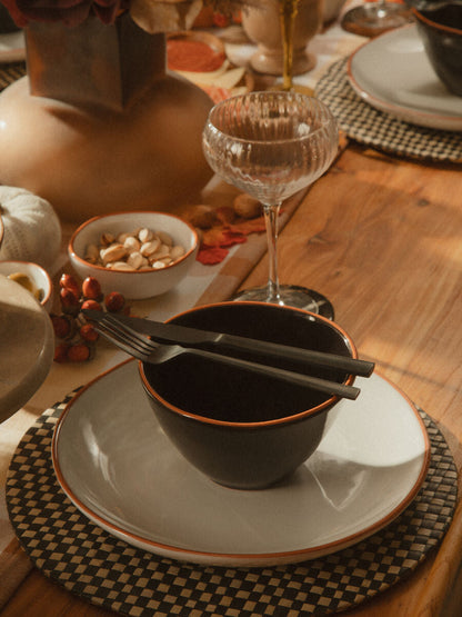 Onyx 16-piece cutlery set by Orsina featuring sleek stainless steel utensils with black handles on a wooden surface.