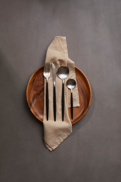 Orsina 16-piece matte silver and black cutlery set including knives, forks, and spoons arranged on a dining table.