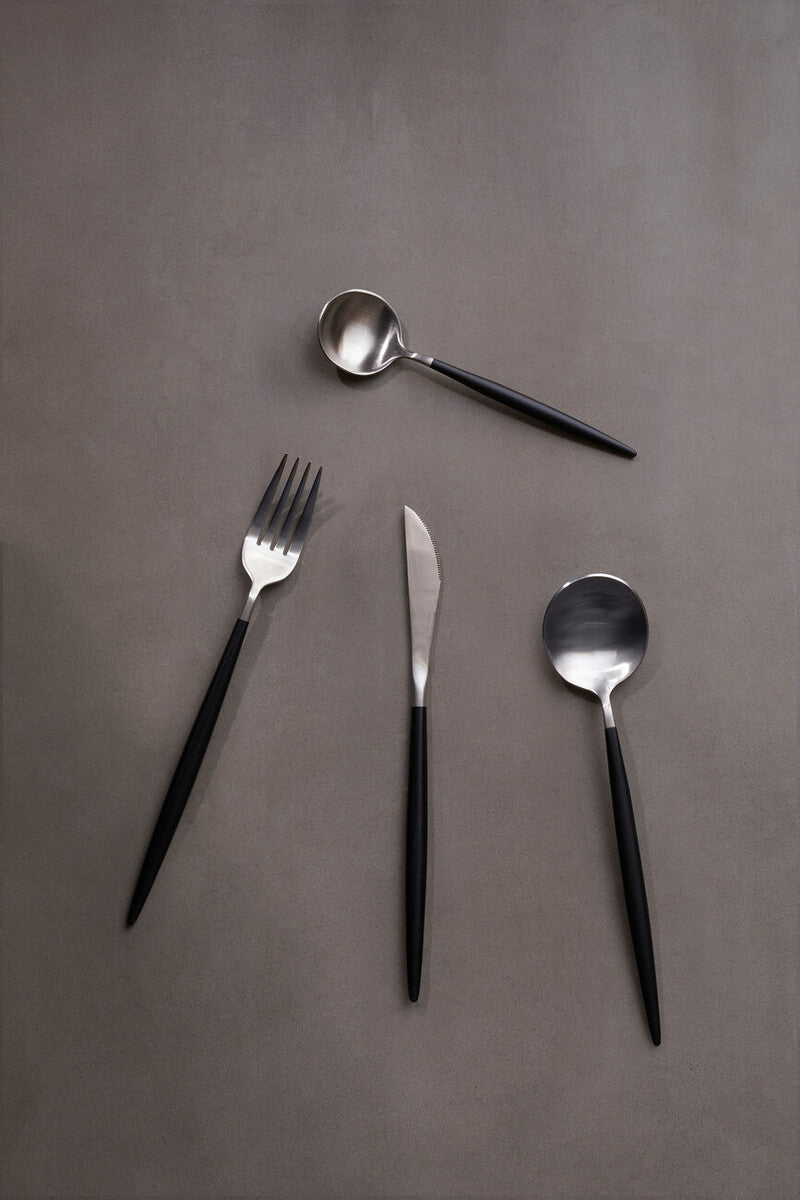 Orsina 16-piece matte silver and black cutlery set with forks, knives, and spoons arranged on a table.