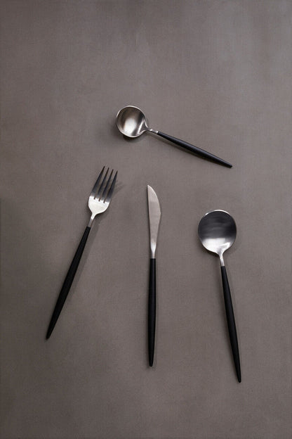 Orsina 16-piece matte silver and black cutlery set with forks, knives, and spoons arranged on a table.