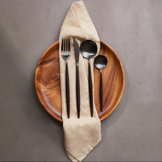 16-piece matte black cutlery set by Orsina, modern retro style with forks, knives, spoons, and serving pieces arranged neatly.