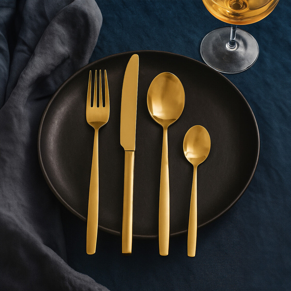Orsina 16-piece gold finish stainless steel cutlery set with forks, knives, spoons arranged on a white background.