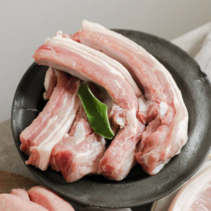 Pork ribs from Primrose Herd, 500g, showing raw, meaty pork ribs with visible bone and marbling on a white surface.