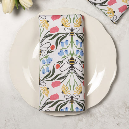 Pair of Avalon Home UK British Bees napkins folded on a plate, featuring bee and floral patterns for elegant table setting.