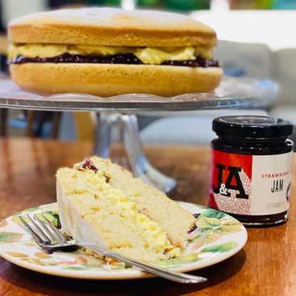 Jar of Janda strawberry jam with fresh strawberries and spreadable texture, showcasing vibrant red fruit and jam swirls.