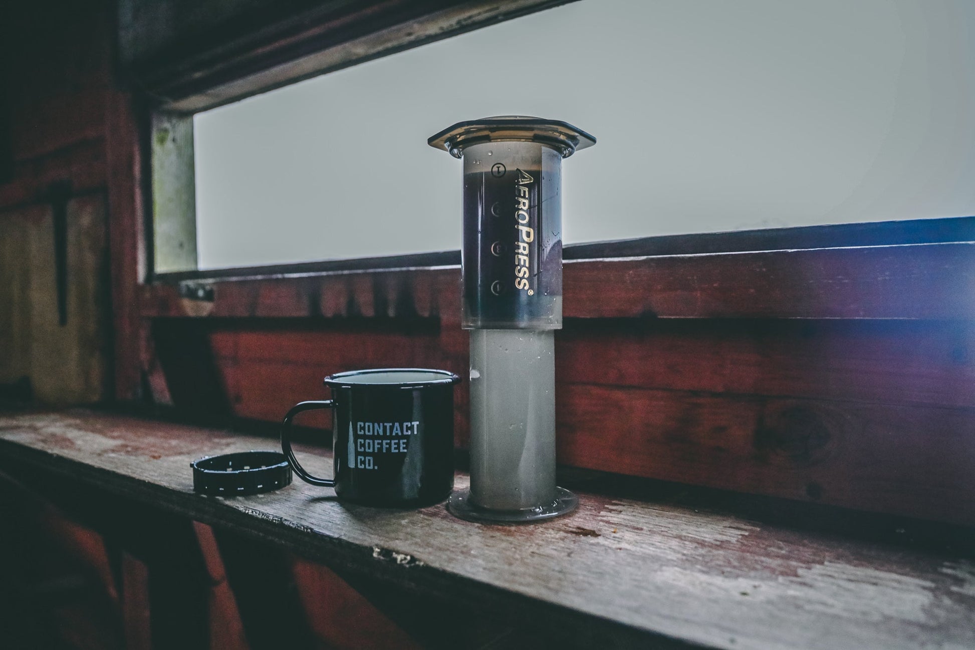 AeroPress Travel Coffee Maker by Contact Coffee Company Ltd., compact portable coffee brewing gear on a clean surface.