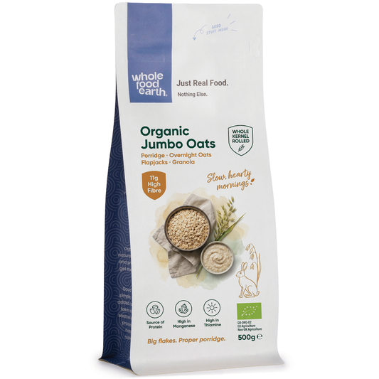 Organic jumbo oats in a clear bowl, showcasing whole cereal oats from Whole Food Earth on a neutral background.