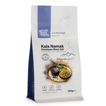 Fine black salt, Kala Namak, from Whole Food Earth, shown in a clear container, highlighting its dark, crystalline texture.