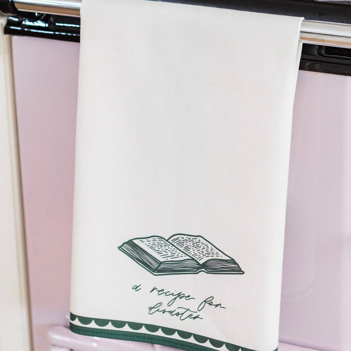 Avalon Home UK recipe for disaster tea towel with colorful printed design, hanging on a kitchen hook.