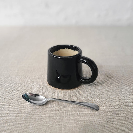 Jet black ceramic espresso mug by Katie L Thompson Designs, featuring a sleek, classic design perfect for coffee enthusiasts.