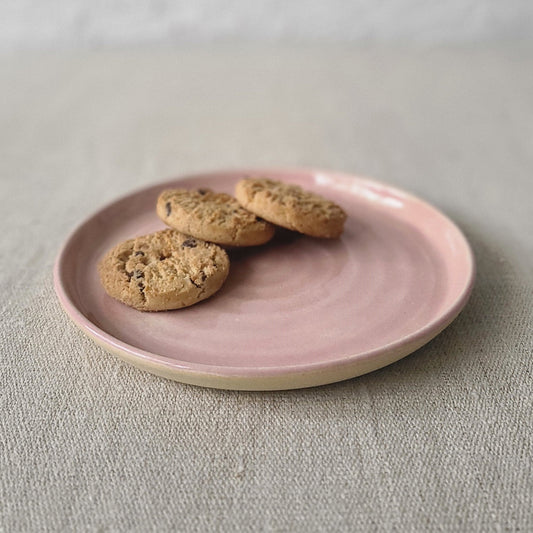 Blush pink classic cake plate by Katie L Thompson Designs, featuring a smooth round surface and elegant design for serving desserts.
