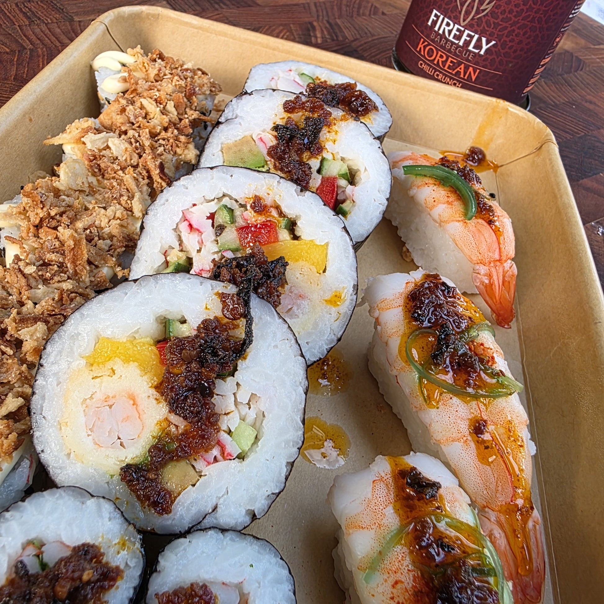 FireFly Barbecue Korean Chilli Crunch spicy hot sauce in a clear glass bottle with a red label, showing bright chili flakes inside.