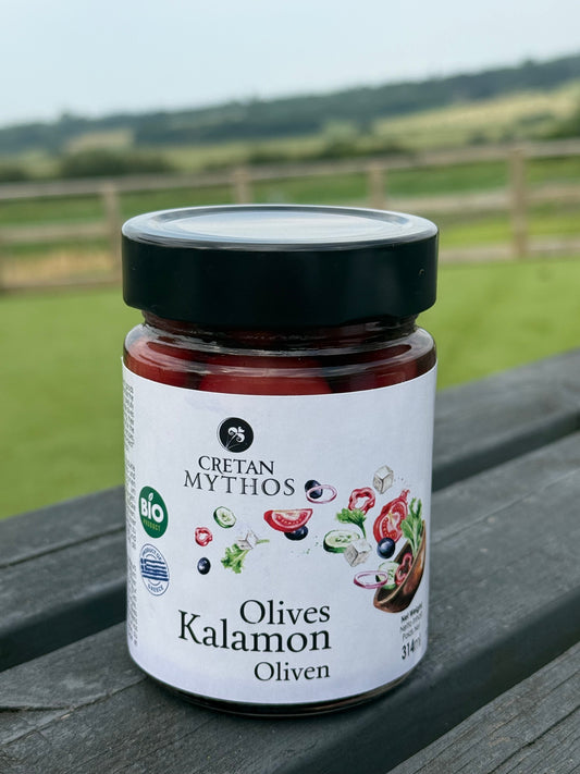 Organic Kalamata olives in brine from Cretan Mythos, Greek olives, shown in a glass jar with a metal lid.