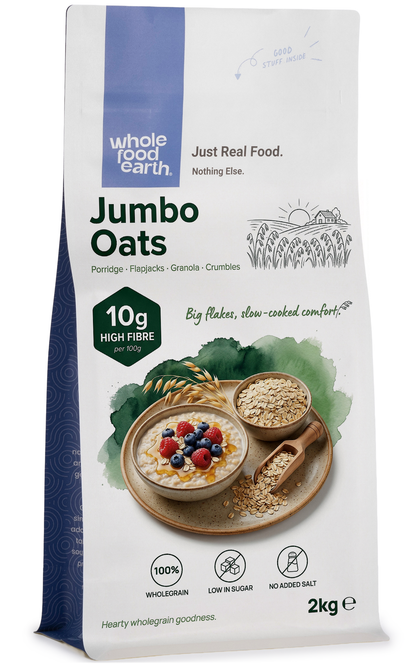 Whole Food Earth Jumbo Oats cereal in a bowl, close-up of textured oats with a spoon on a wooden surface.