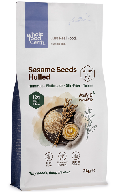 Hulled sesame seeds from Whole Food Earth, showing small white seeds in a clear bowl on a wooden surface.