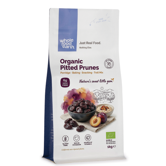 Dried organic pitted prunes from Whole Food Earth in a clear bowl, showcasing dark, wrinkled fruit pieces on a white background.