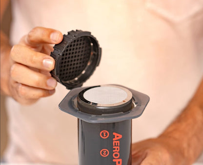 Stainless steel AeroPress filter by Contact Coffee Company Ltd. for coffee brewing, shown in a close-up image.