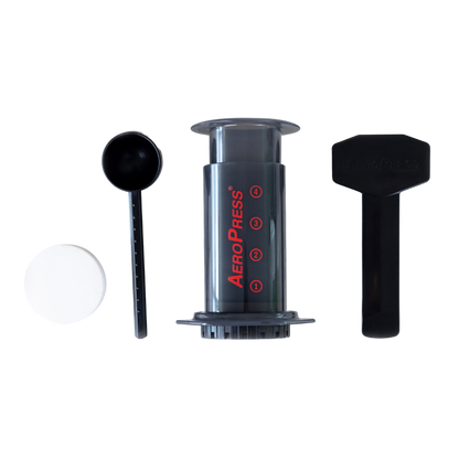 AeroPress Travel Coffee Maker from Contact Coffee Company Ltd. shown with brewing components on a wooden surface.