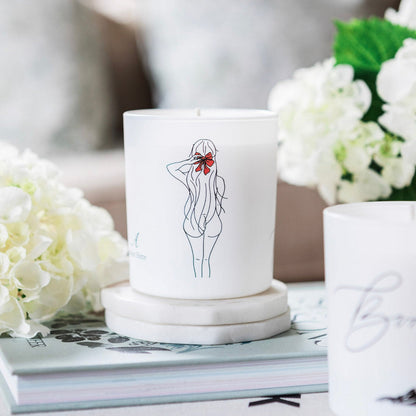Natural wax glass candle by Avalon Home UK, with a clear glass container and a lit cotton wick, emitting a warm glow.