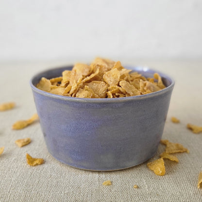 Amethyst purple breakfast bowl by Katie L Thompson Designs filled with cereal, showcasing a stylish ceramic design.