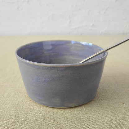 Amethyst purple ceramic breakfast bowl with matching spoon, designed by Katie L Thompson for serving cereals or yogurt.