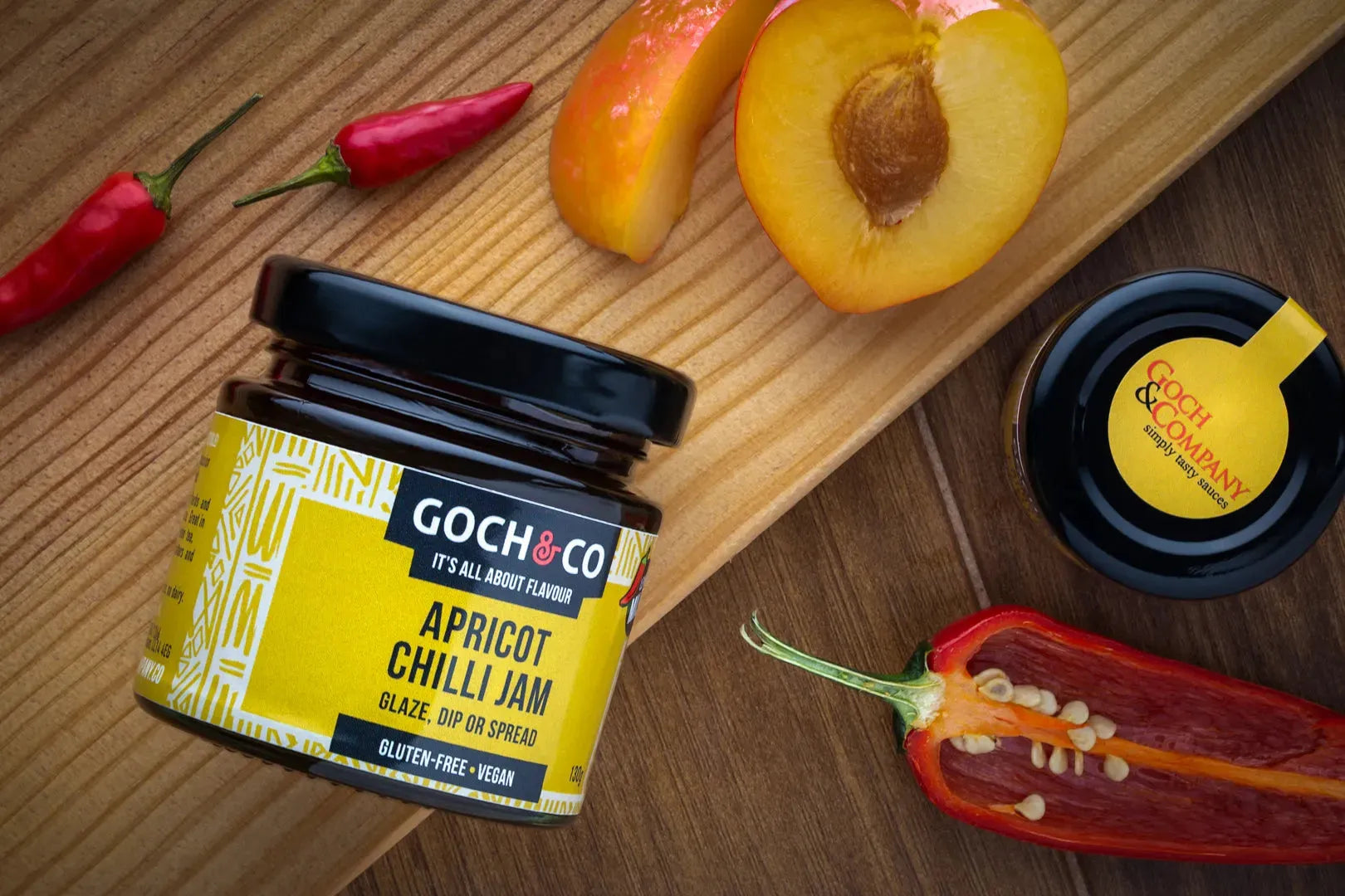Close-up of a jar of Goch & Co Apricot Chilli Jam showing the vibrant orange jam with chili flakes inside.