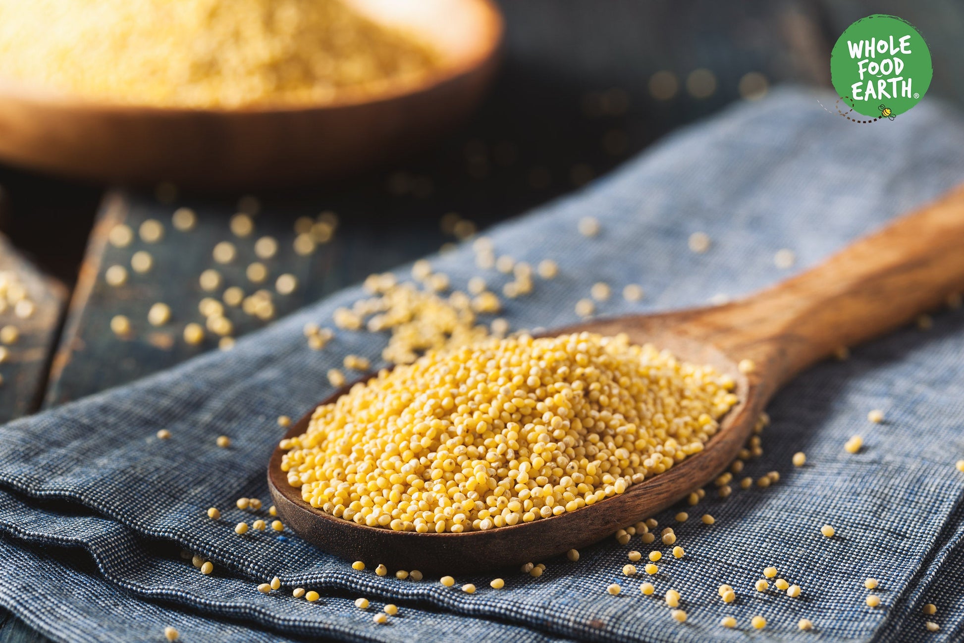 Whole Food Earth millet grain in a bowl, showcasing small, round, yellow millet seeds for healthy cooking and baking.