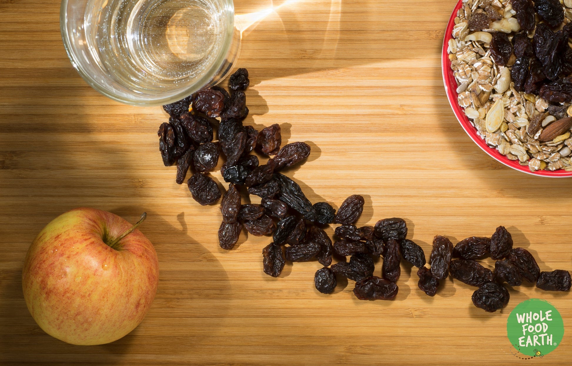 Close-up of jumbo black raisins from Whole Food Earth, dried fruit with glossy, dark, wrinkled appearance in a clear container.