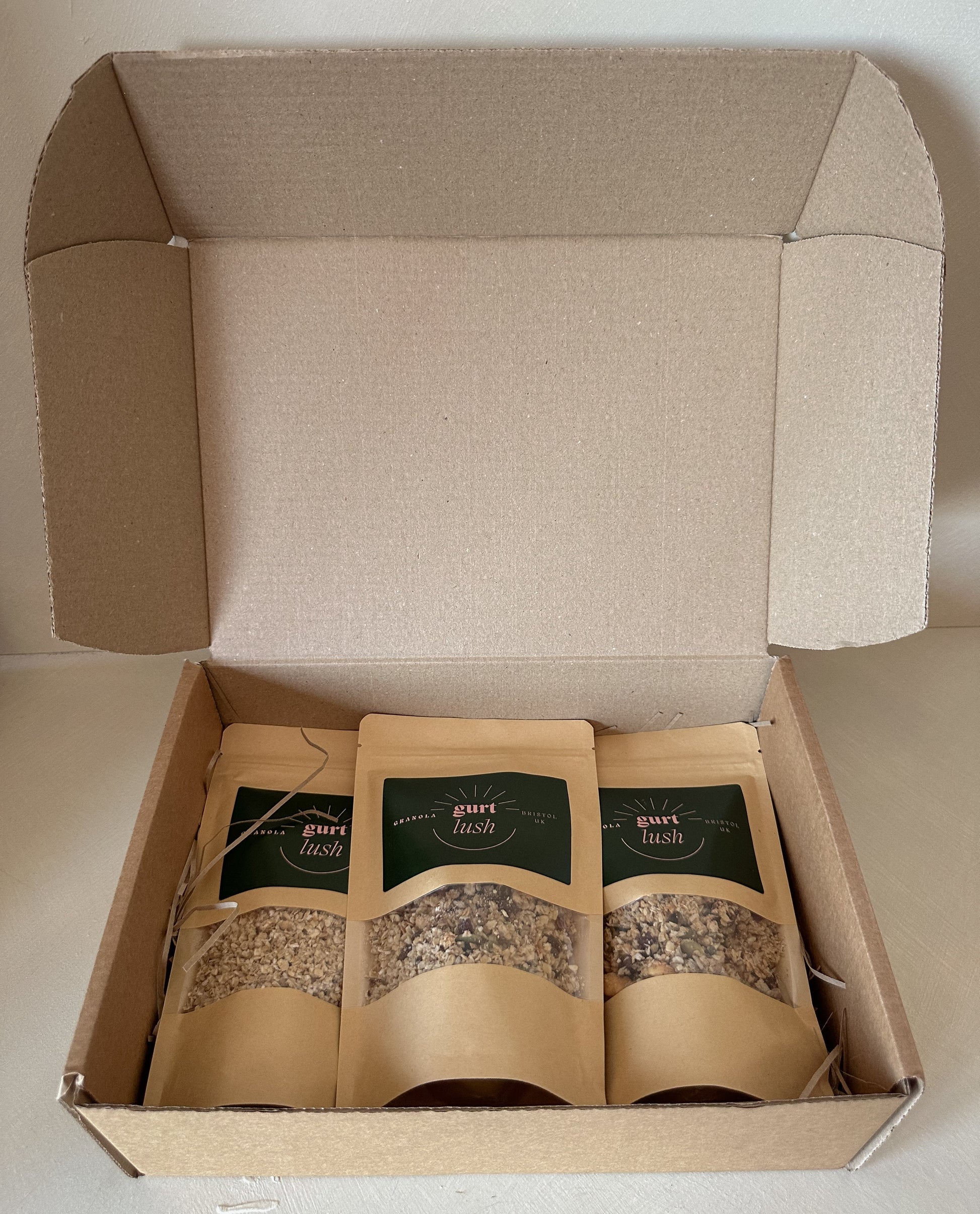 Gurt Lush Food Co granola taster box with assorted granola samples in a clear container, featuring various textures and ingredients.