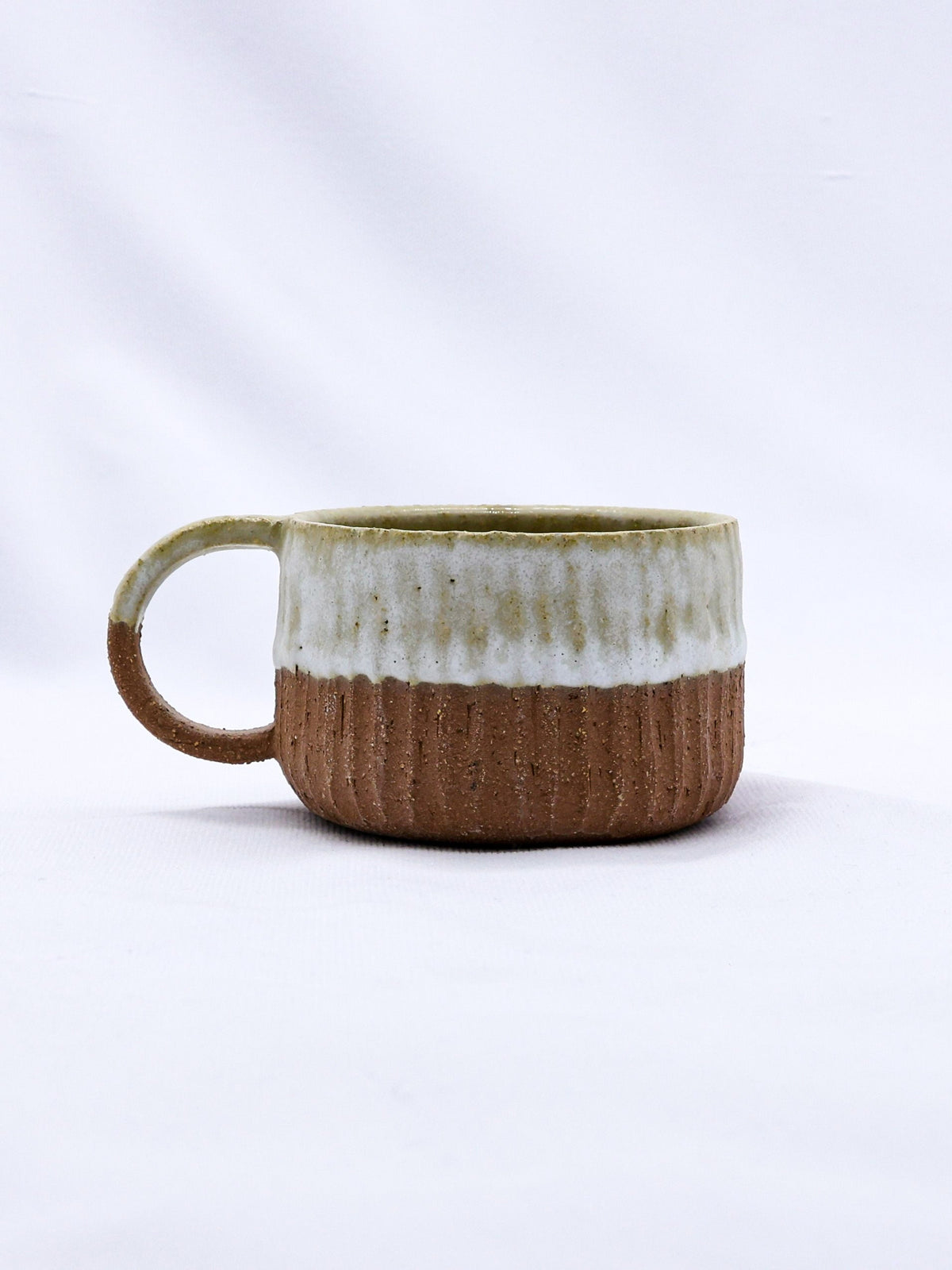 Bianca Arte handmade ceramic terra stoneware mug by Ribera Handmade Ceramics, featuring a rustic, textured surface and organic shape.