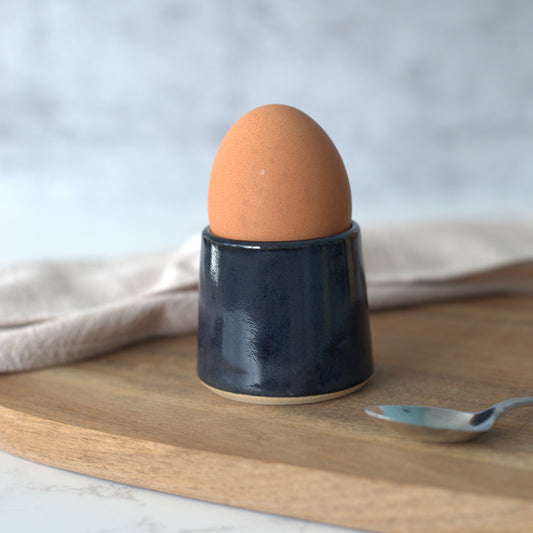 Jet black classic egg cup by Katie L Thompson Designs, featuring a sleek, minimalist ceramic egg holder on a white background.