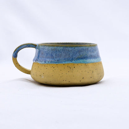 Handmade stoneware ceramic mug with a blue glaze from Ribera Handmade Ceramics, featuring a rounded shape and textured surface.