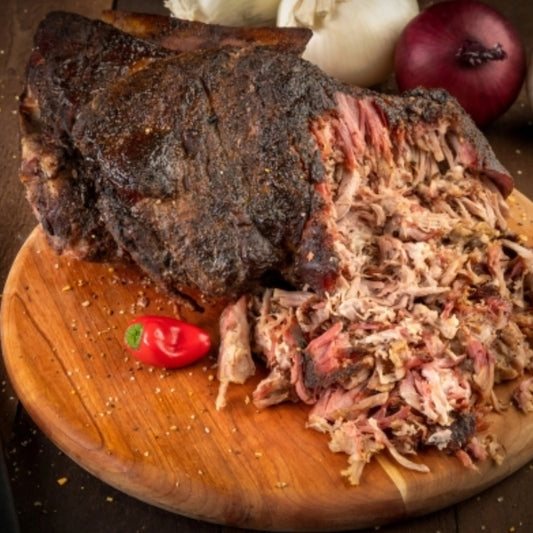 Cooked Primrose Herd Boston Butt pork joint showing tender, juicy meat with a crispy crust, ready for slicing.