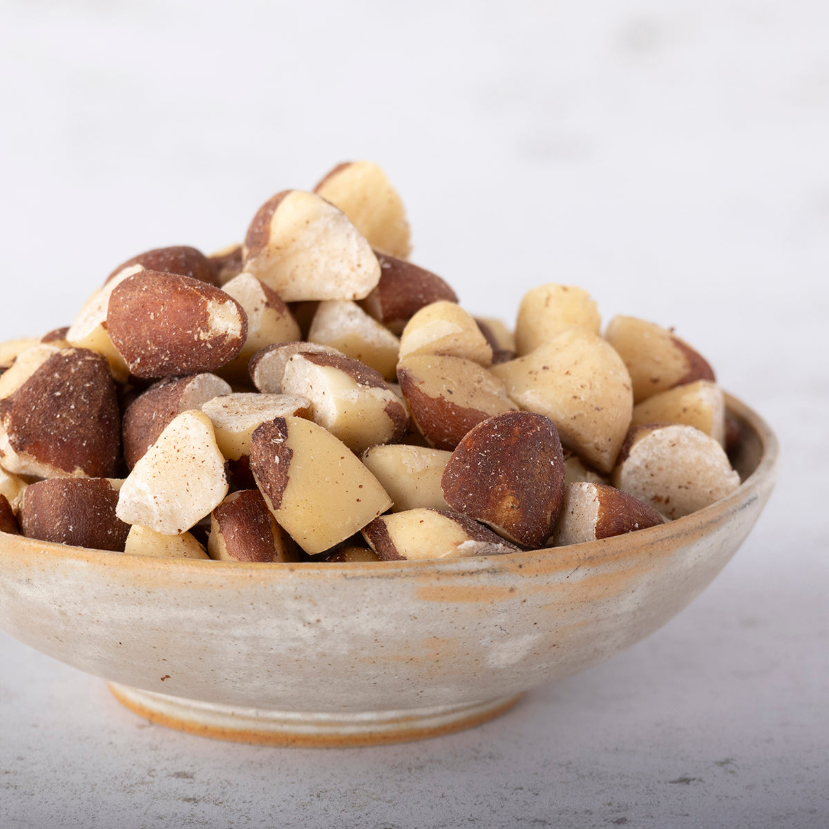 Broken Brazil nuts from Whole Food Earth in a bowl, showcasing their large, irregularly shaped pieces and natural brown color.