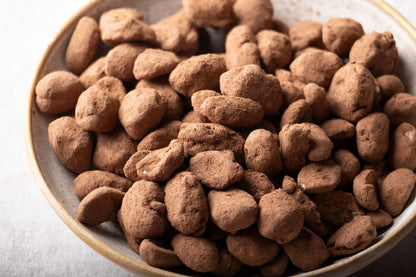 Whole Food Earth caramelized cocoa peanuts, crunchy nuts and seeds coated in sweet cocoa caramel, displayed in a bowl.