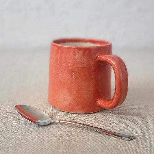 Cherry red ceramic standard mug with a matching spoon from Katie L Thompson Designs, featuring a smooth finish and classic shape.