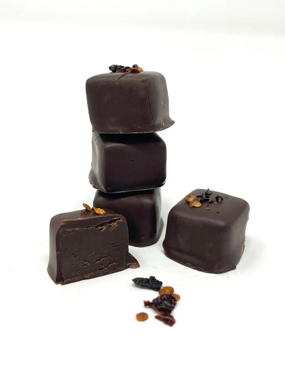 Stack of Gorvett & Stone chipotle chili chocolates showing dark chocolates with chili pepper pieces on top.